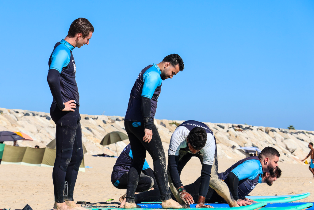 Instrutor a ensinar a técnica de levantar na prancha durante aula de surf na praia