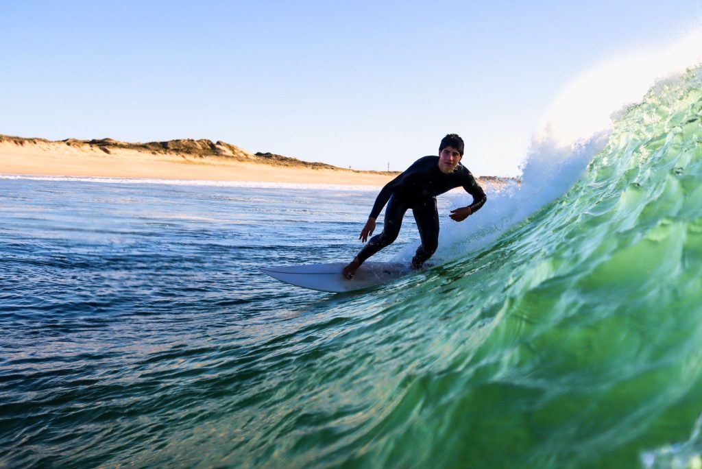 Surfista da Green Wave dentro de uma onda tubo em Cascais, com a duna ao fundo